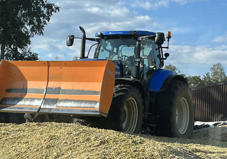 Traktor mit Schaufel beim Umsetzen von Erntegut