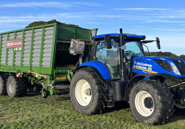 New-Holland-Traktor mit Ladewagen bei der Feldarbeit im Münsterland